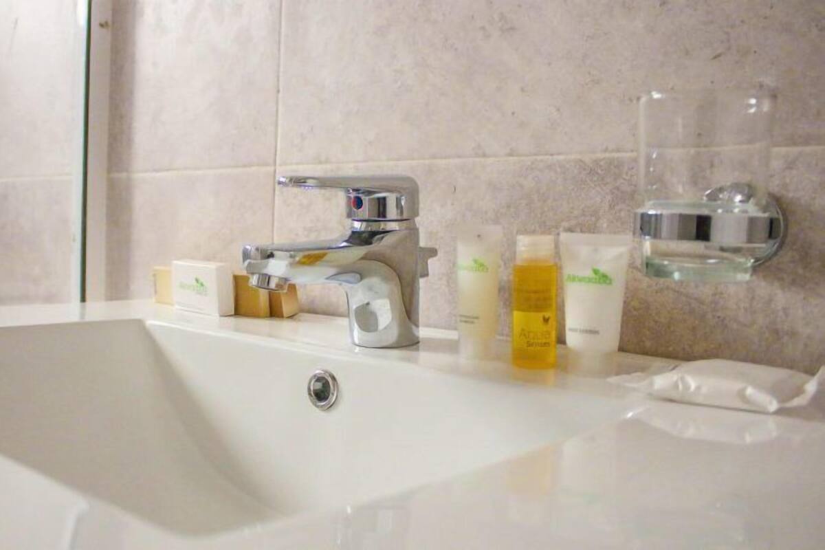 A modern bathroom with a white sink, chrome faucet, and toiletries on the countertop.
