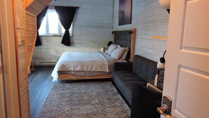 Un dormitorio con cama, sofá, alfombra y puerta.