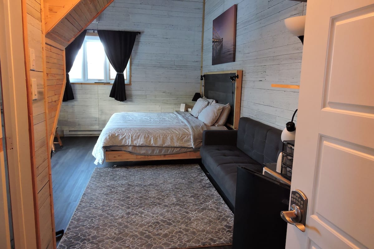 Un dormitorio con cama, sofá, alfombra y puerta.
