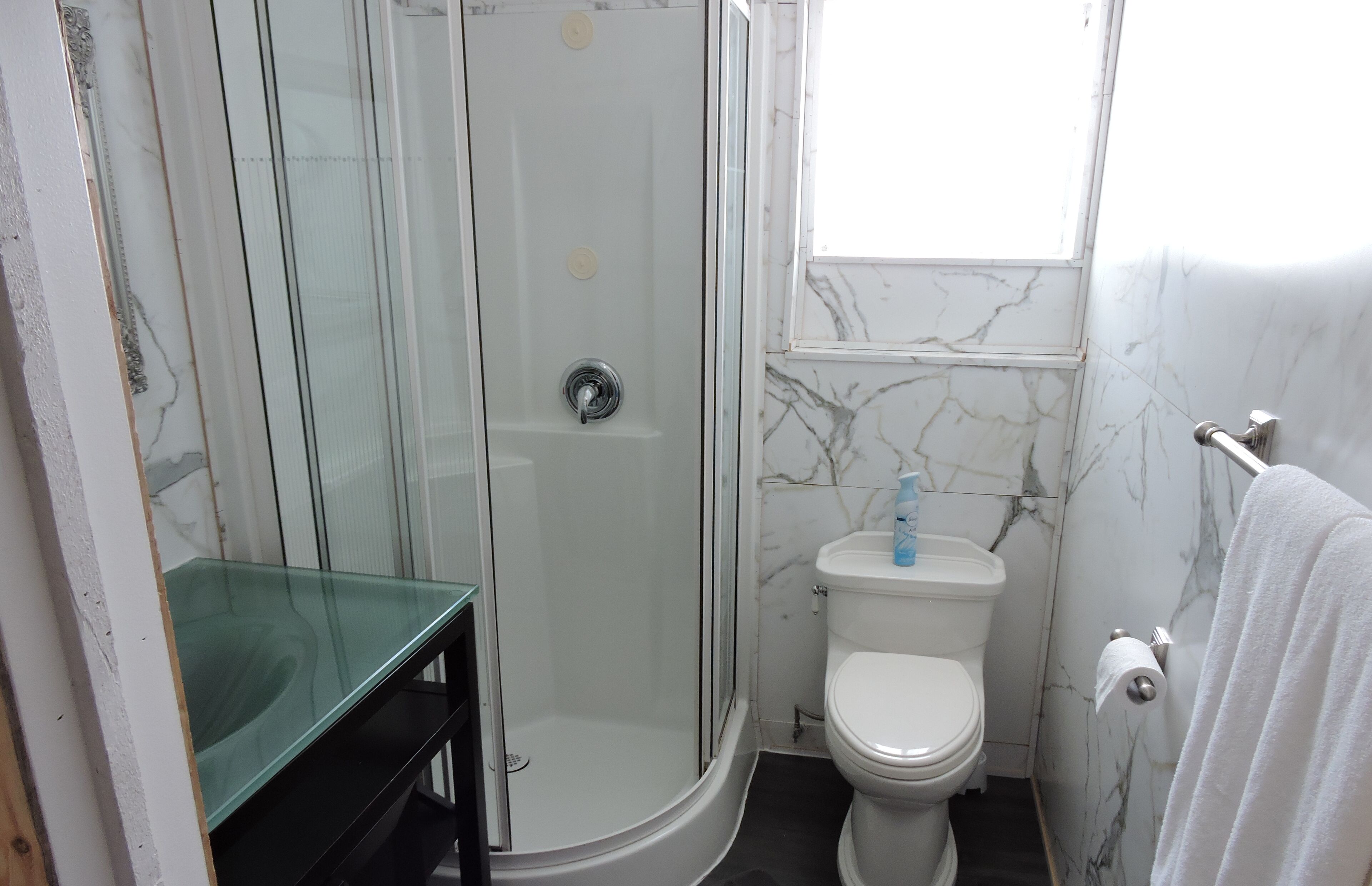 A bathroom with a glass-enclosed shower, a toilet, and a sink.