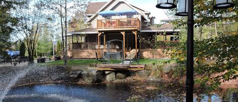 A house with a wooden deck, a pond, and a street lamp.