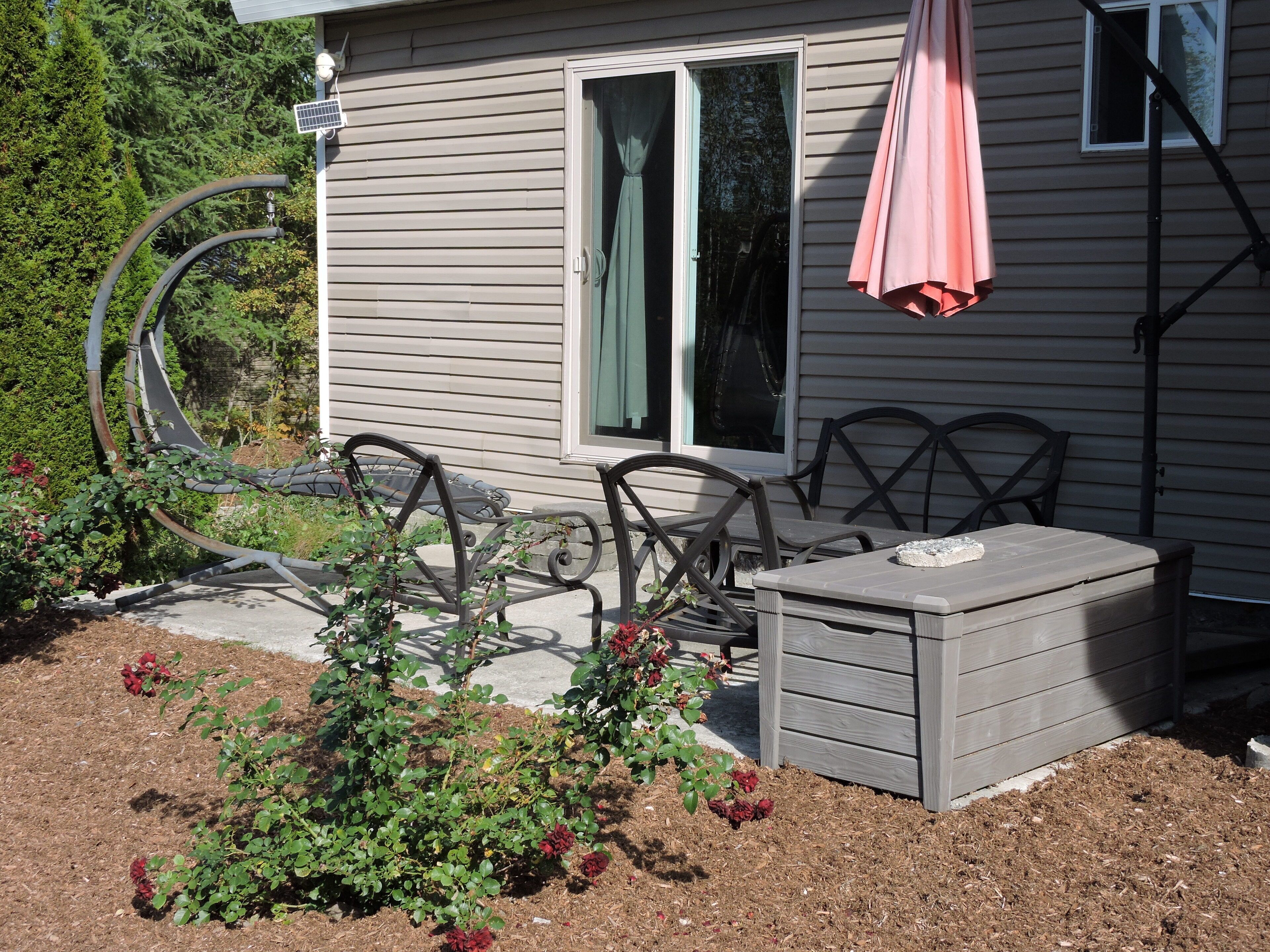 Un patio con mobiliario exterior, una mesita y un baúl.