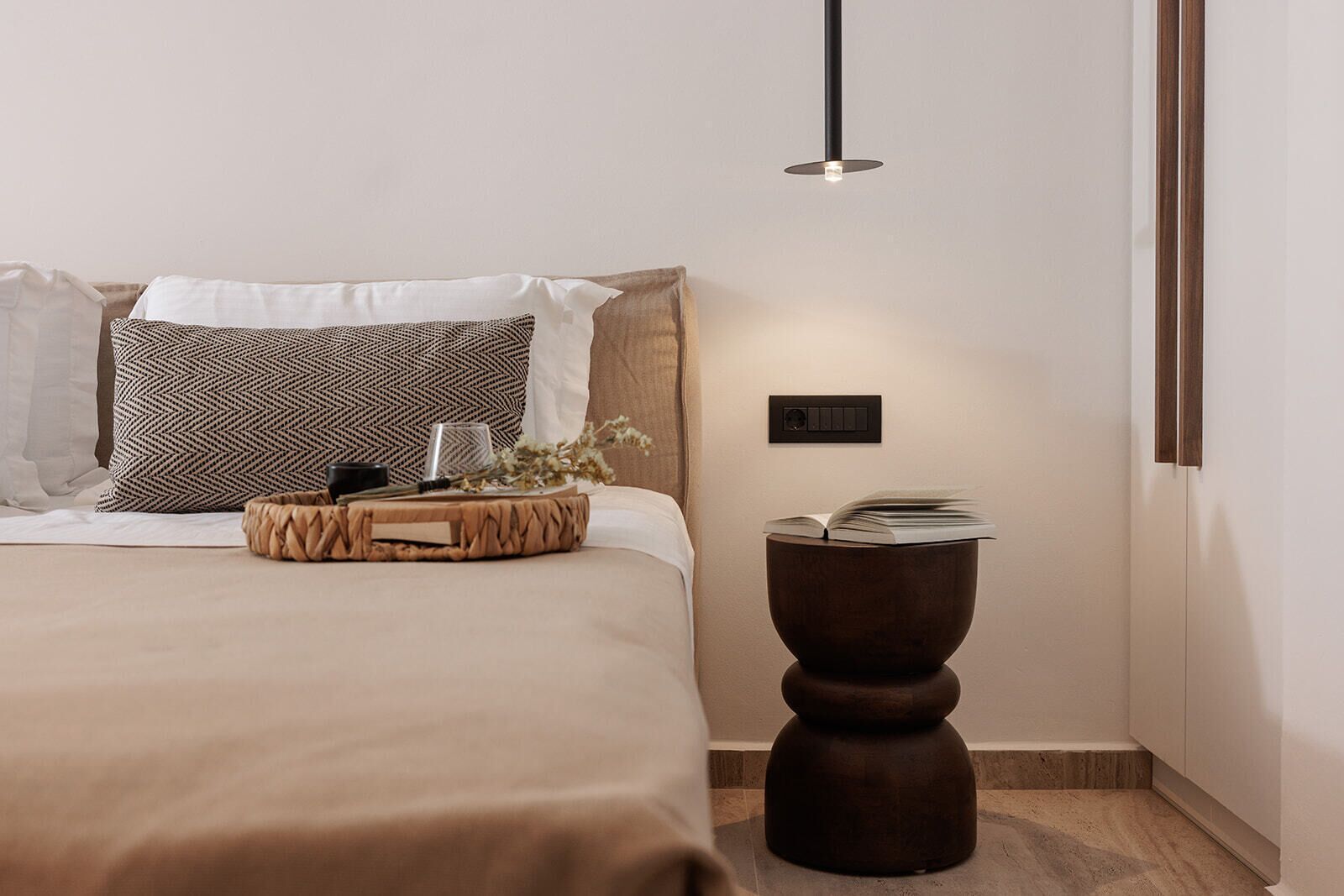 A neatly arranged bedroom with a bed, bedside table, and a wall-mounted light fixture.