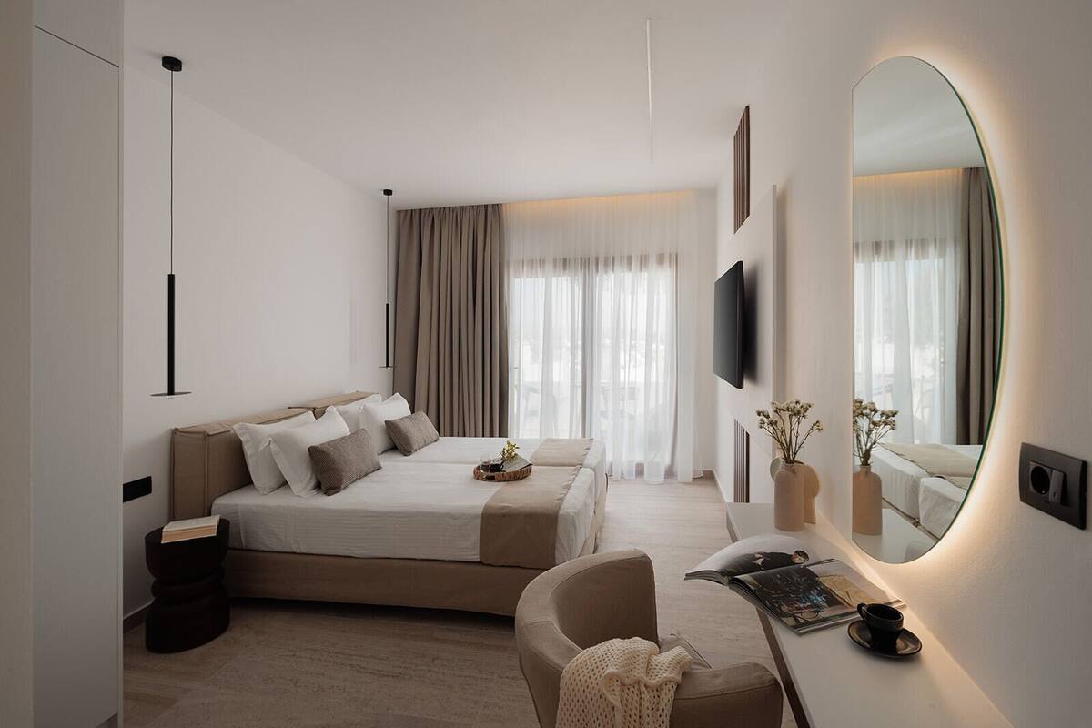 Une chambre moderne avec un grand lit, un bureau avec un ordinateur, une chaise et un grand miroir.