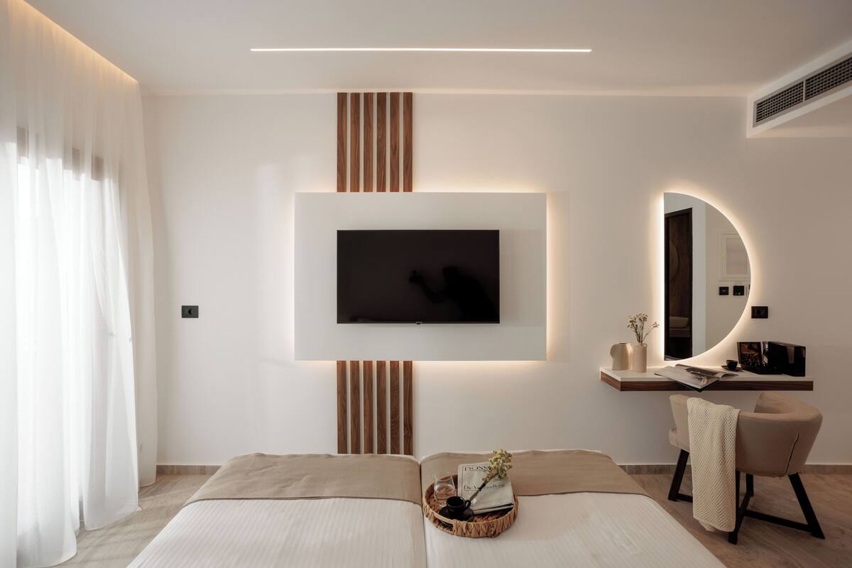 Une chambre à coucher moderne avec un téléviseur à écran plat fixé au mur, une table de chevet avec une lampe et un fauteuil.