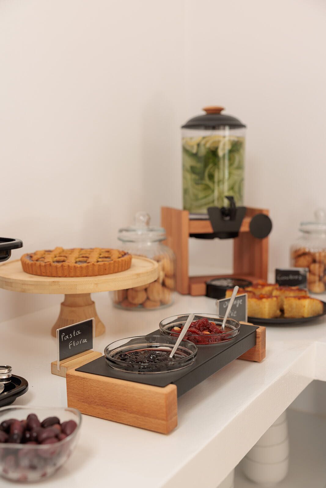 A buffet with various food items including a pie, jars of preserves, and a coffee station.