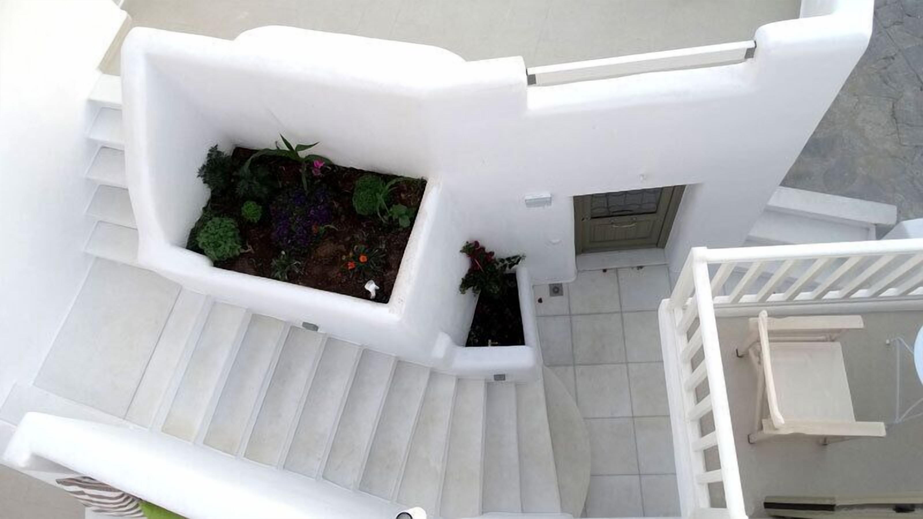 A white staircase leading to a landing with a small garden area.