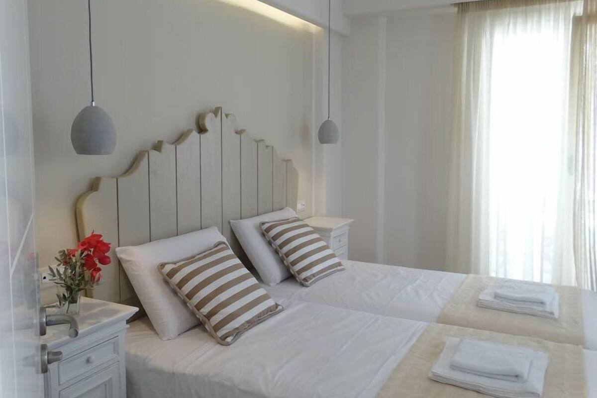 Une chambre d’hôtel moderne avec un grand lit, deux tables de chevet et une petite table d’appoint.