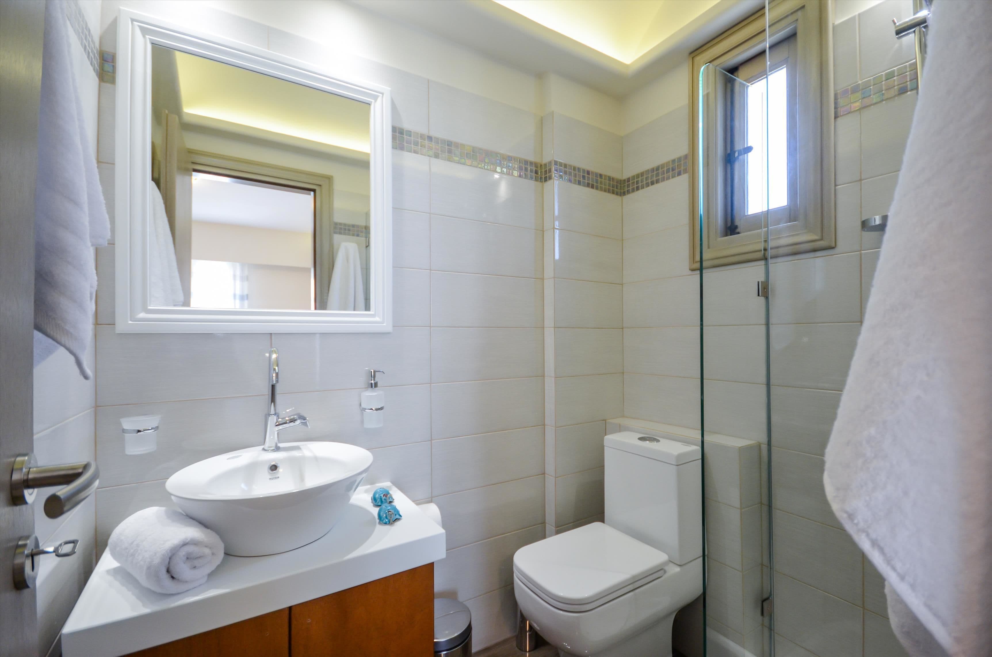 A modern bathroom with a white sink, mirror, and toilet.