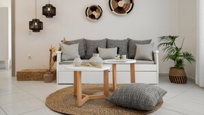 A modern living room with a white sofa, two side tables, and decorative wall art. - Ormos Holiday Studios (Naxos)