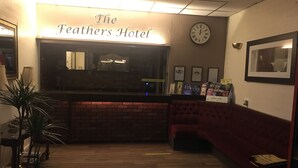 The Feathers Hotel reception area with a clock, framed pictures, and a sign indicating a 6-meter social distancing guideline. - The Feathers Hotel (Blackpool)