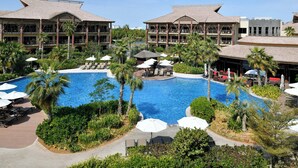 A resort with a large central pool surrounded by palm trees and lounge chairs. - Lapita, Dubai Parks and Resorts, Autograph Collection (Dubai)