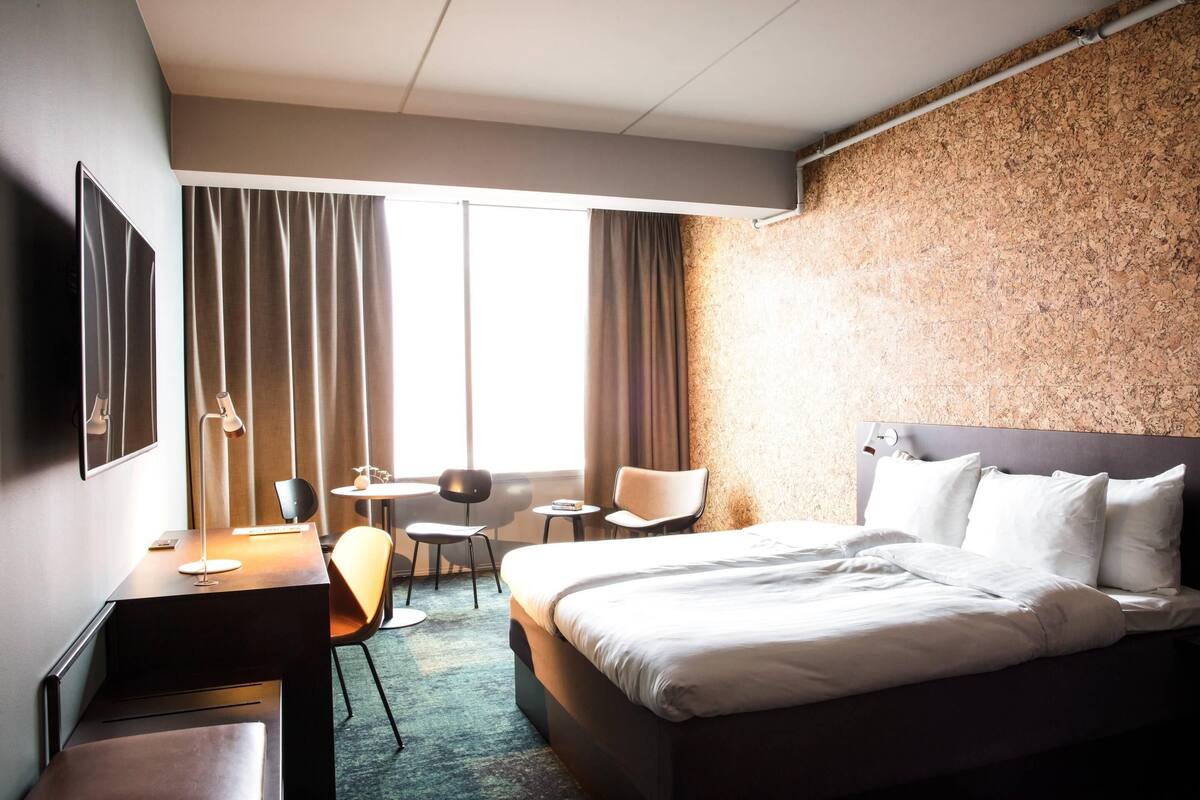 Une chambre d’hôtel avec un lit, un bureau, une chaise et une petite table.