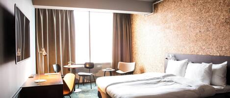 Una habitación de hotel con cama, escritorio, silla y una mesita.