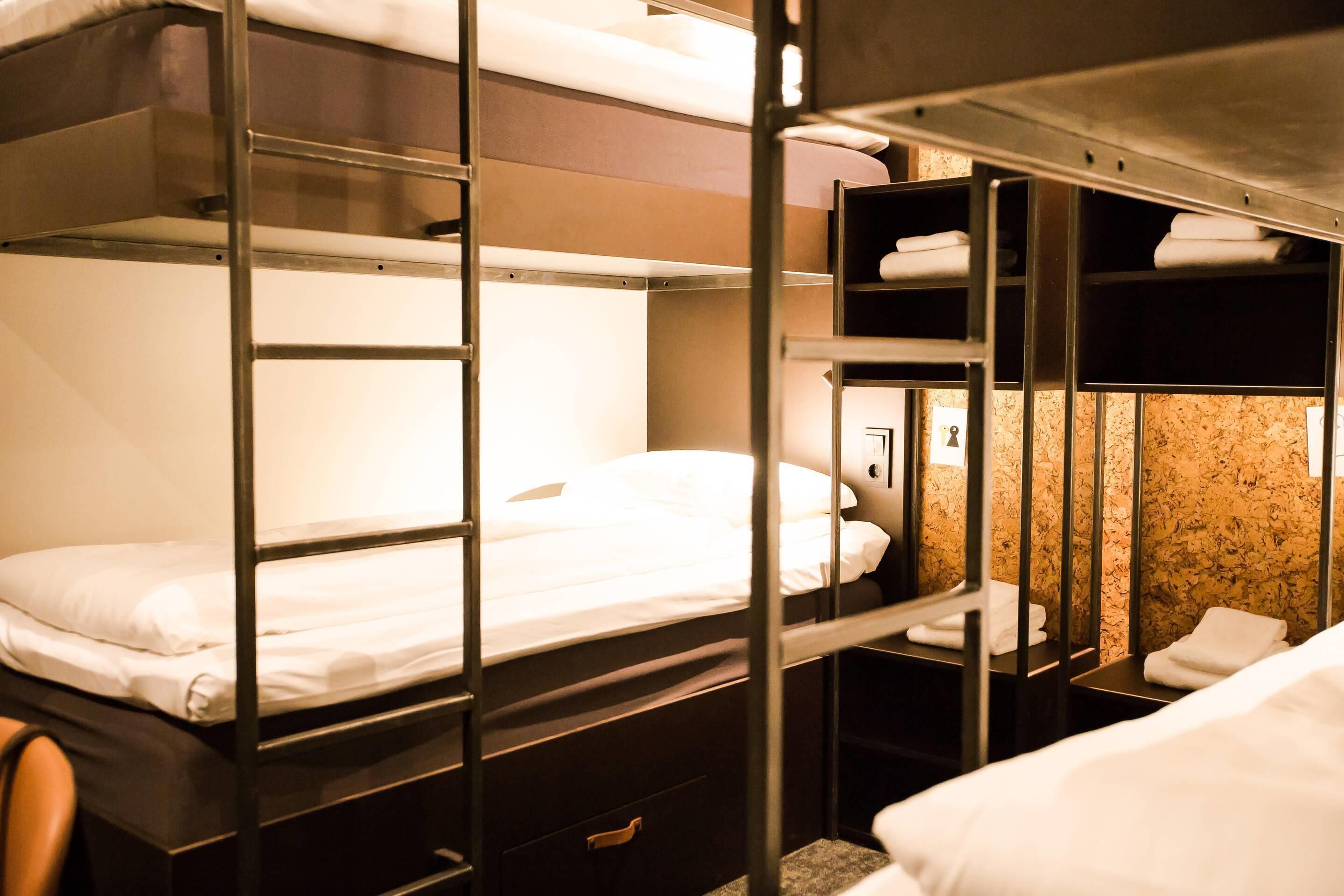 A bunk bed room with a wooden headboard, a small bedside table, and a mirror.