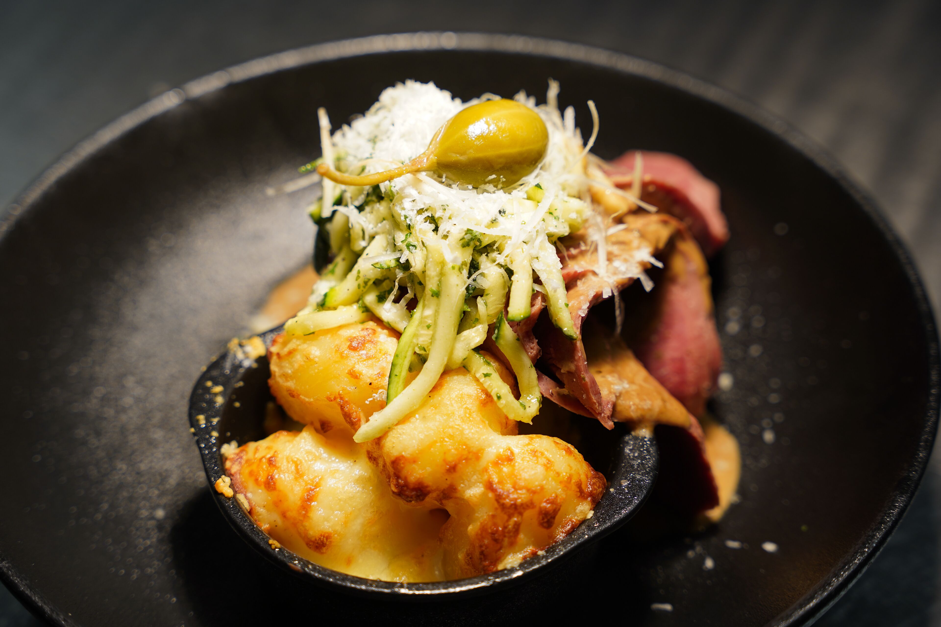 Ein Teller mit Käse, Zucchini und einer grünen Olive.