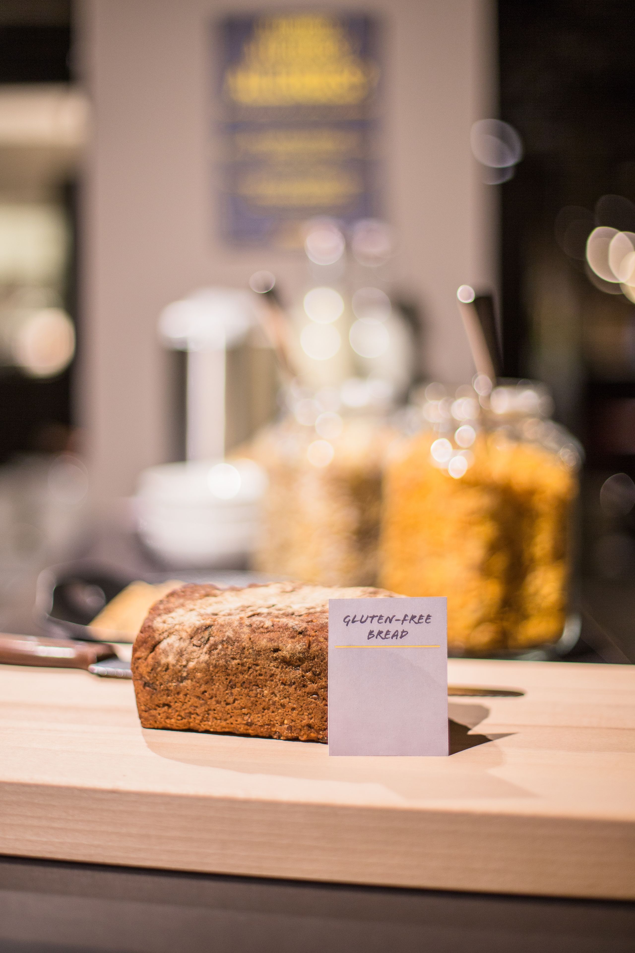 A loaf of gluten-free bread on a wooden table with a sign indicating it is gluten-free.