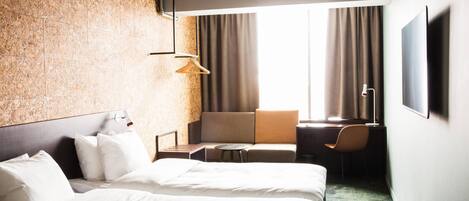A hotel room with a large bed, a desk, a chair, and a sofa.