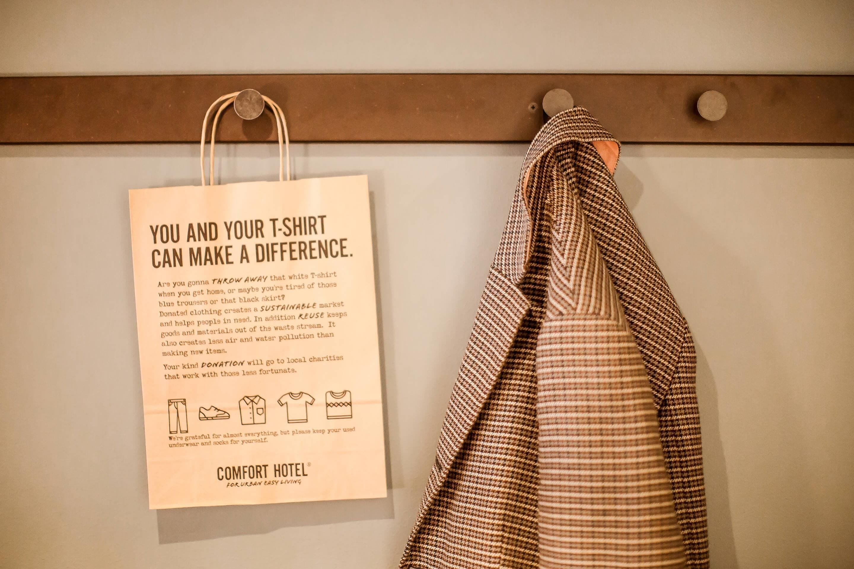 A white wall with a hanging paper bag and a striped towel.