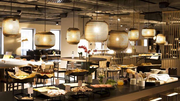 Un comedor moderno con lámparas colgantes, una barra de buffet con diversos alimentos y un diseño de interiores contemporáneo.