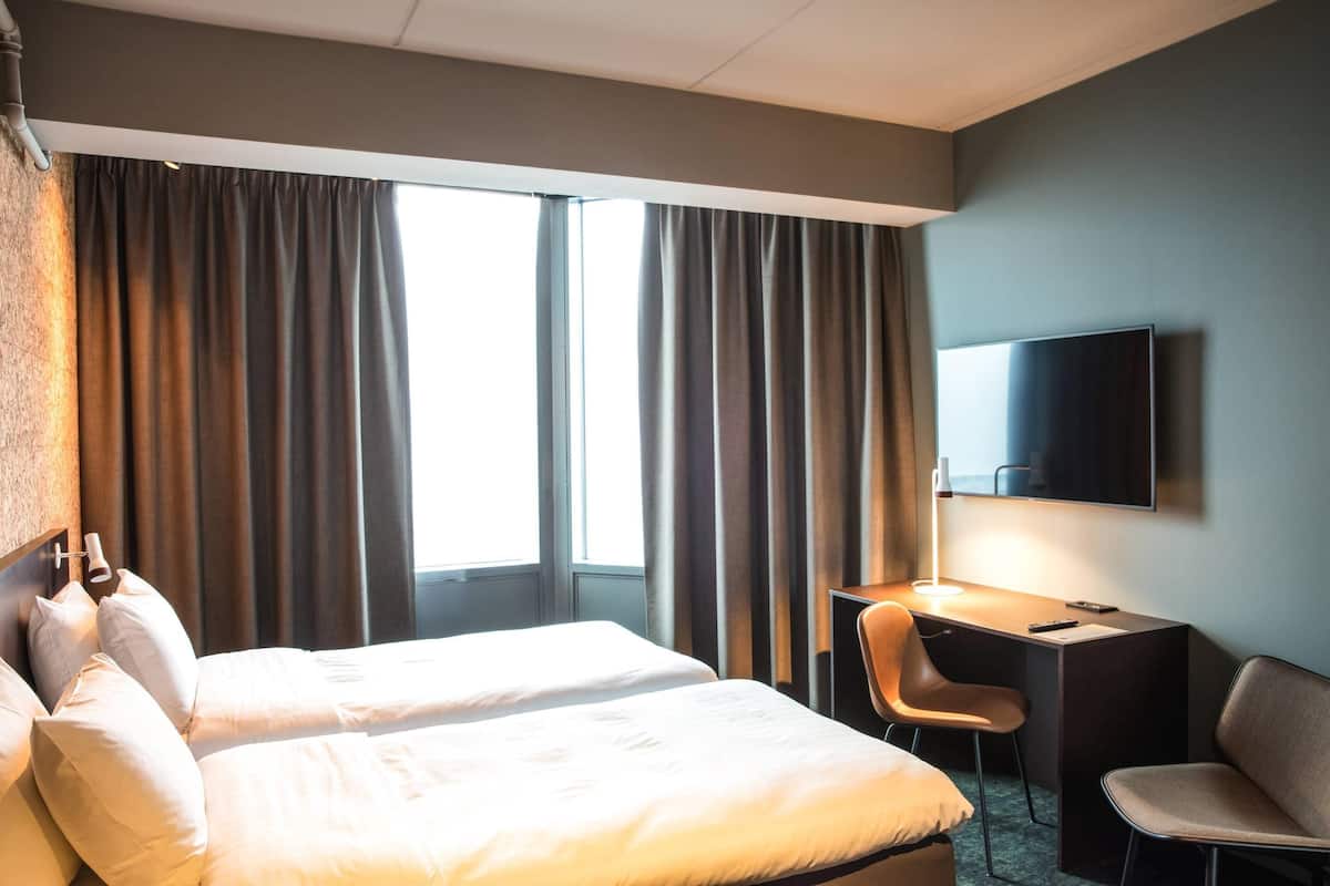 Une chambre d’hôtel avec deux lits, un bureau, une chaise et un téléviseur.