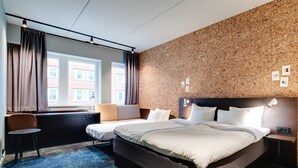 Habitación de hotel con una cama grande, un escritorio, una silla y vistas a la ciudad.