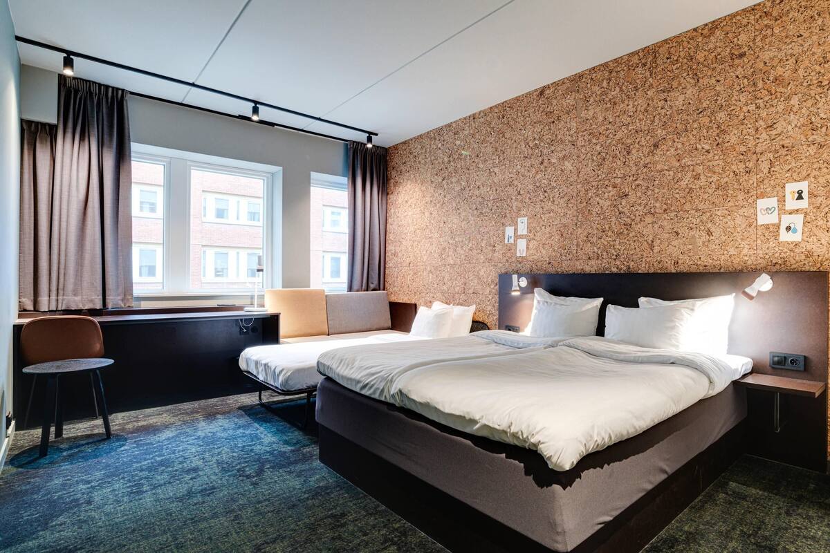 Une chambre d’hôtel avec un grand lit, un bureau, une chaise et une vue sur la ville.