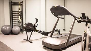 Un gimnasio con una bicicleta estática, elíptica y pelotas de ejercicio.