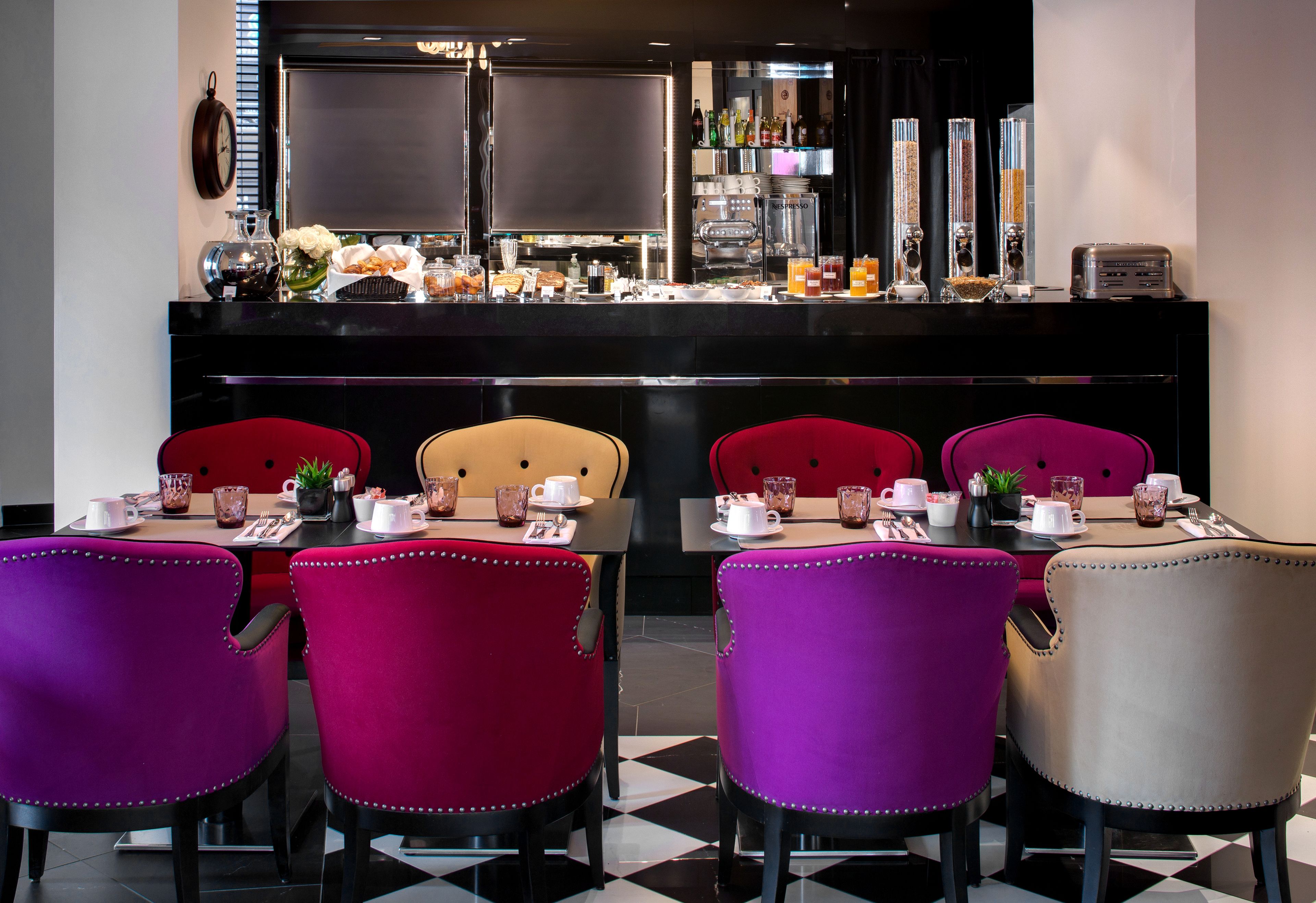 A dining area with a bar, red and beige chairs, and a checkered floor.