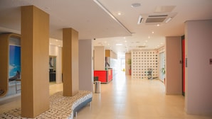 A modern hotel lobby with a central seating area, a reception desk, and a wall with circular patterns. - ibis Styles Birigui (Birigui)