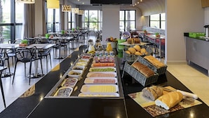 A buffet setup with various food items and a television screen above. - ibis Styles Birigui (Birigui)