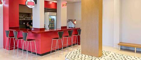 A modern bar area with red accents, a central column, and a circular seating arrangement around a shoe display.