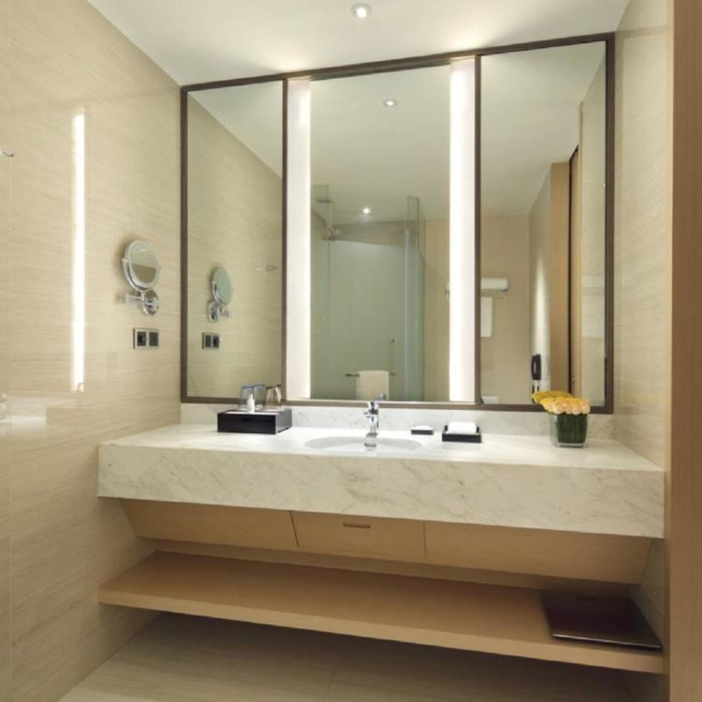 A modern bathroom with a large mirror, a sink, and a toilet.