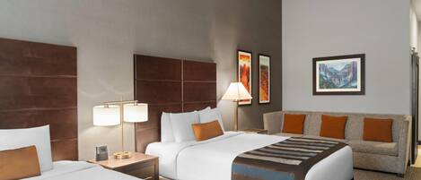 Ein Hotelzimmer mit zwei Betten, einem Schlafsofa, einem Nachttisch und einer Lampe.
