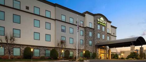 A hotel with a stone facade, multiple windows, and a covered entrance.