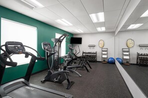 Un gimnasio con cintas de correr, elípticas y pelotas de ejercicio.
