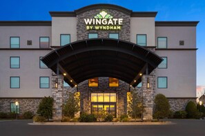 Un hotel llamado Wingate by Wyndham con fachada de piedra, ventanas amplias y un acceso cubierto.