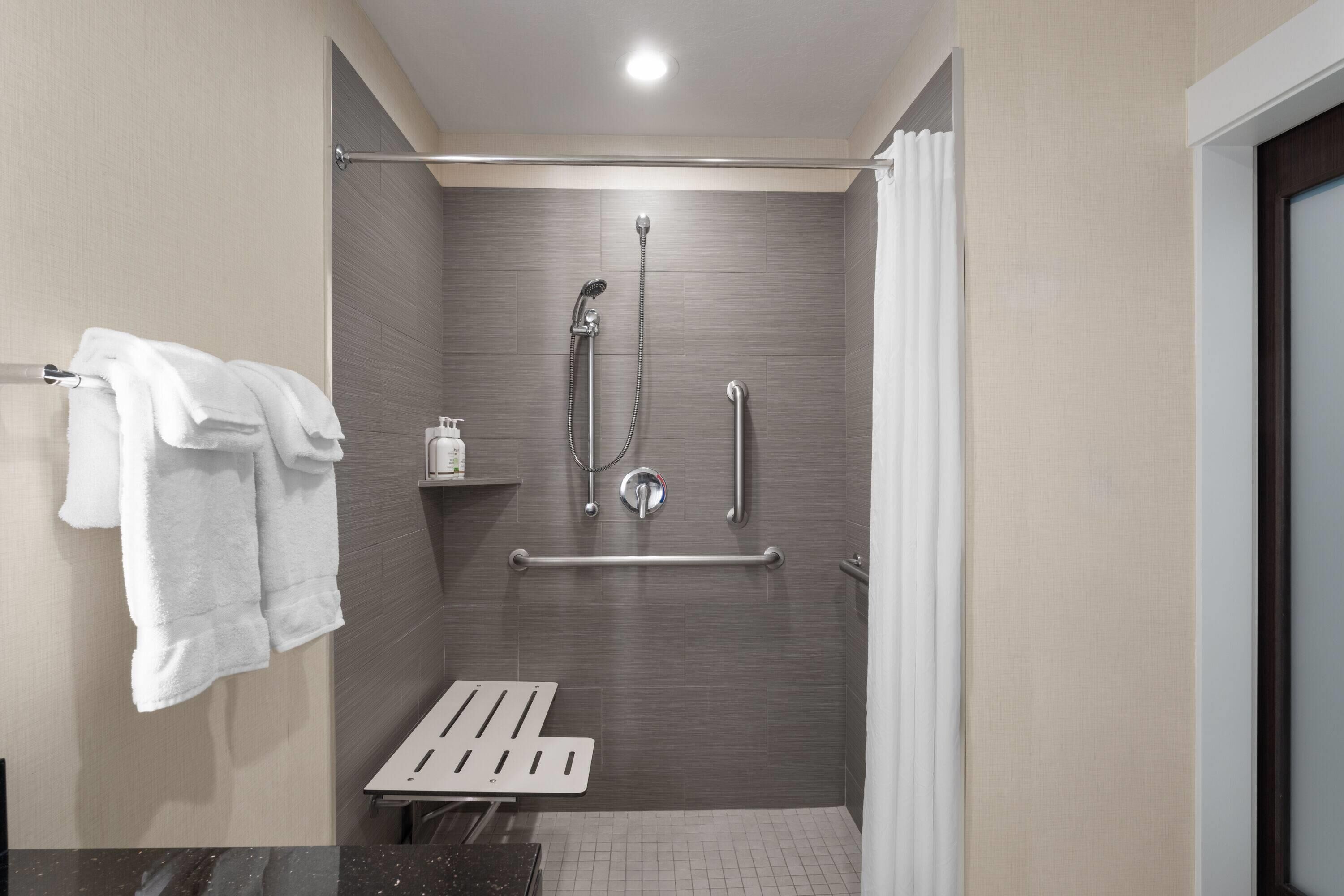 Ein modernes Badezimmer mit Dusche, Haltegriffen und Handtuchhalter.