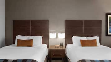 A hotel room with two beds, a nightstand with a lamp, and a framed picture on the wall.