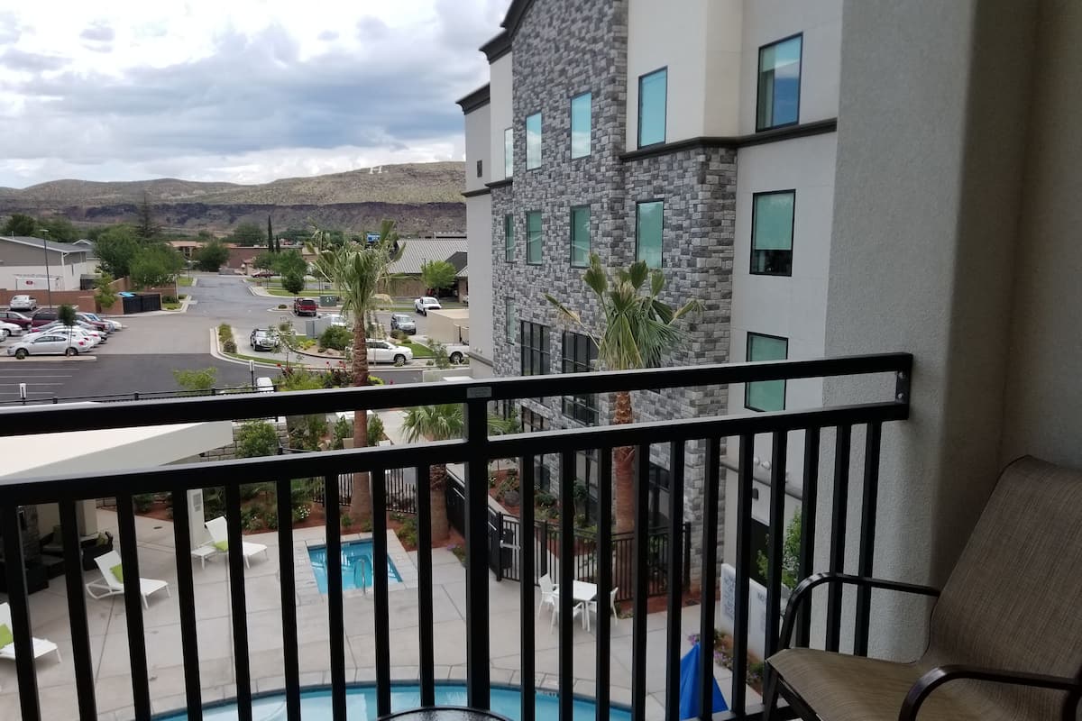 A balcony with a pool, a view of a parking lot, and a building with stone facade and multiple windows.