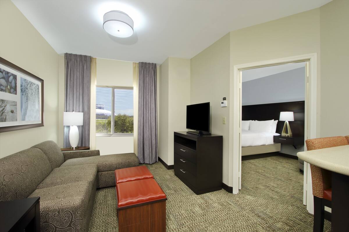 A hotel room with a sofa, a TV, a desk, and a bed.