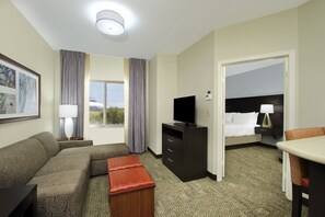 A hotel room with a sofa, a TV, a desk, and a bed. - Staybridge Suites Houston - Medical Center by IHG (Houston)