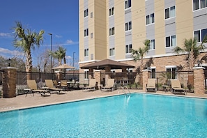 A hotel pool area with lounge chairs and umbrellas, surrounded by a fence and palm trees. - Staybridge Suites Houston - Medical Center by IHG (Houston)