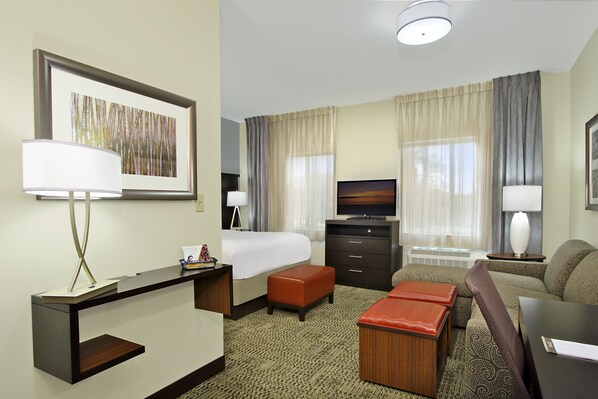 A hotel room with a bed, a desk, a television, a sofa, and a carpeted floor. - Staybridge Suites Houston - Medical Center by IHG (Houston)