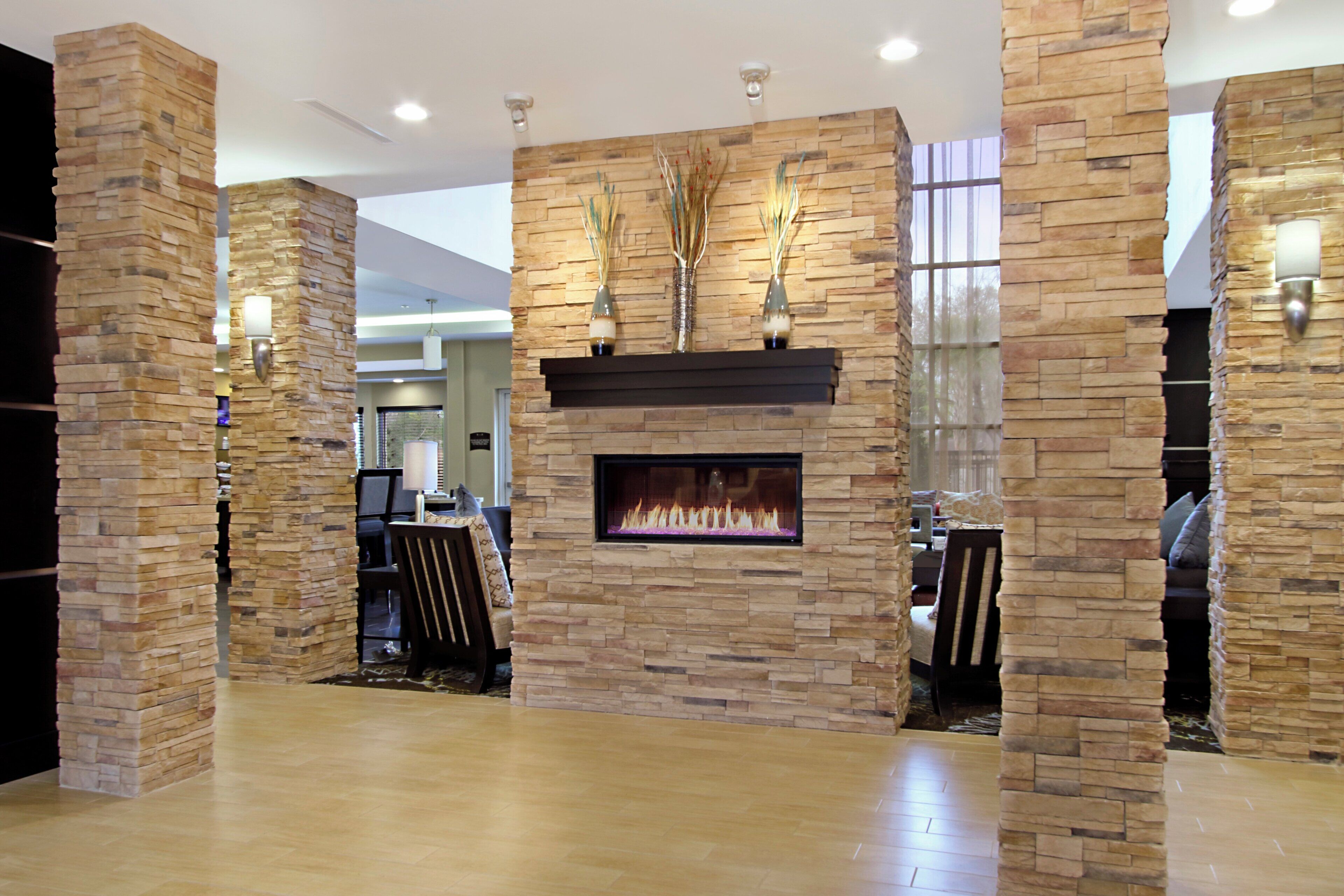 A modern interior with a stone fireplace, seating area, and decorative vases.