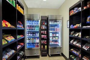 A vending area with multiple beverage and snack options, including bottled water, sodas, and various packaged snacks. - Staybridge Suites Houston - Medical Center by IHG (Houston)