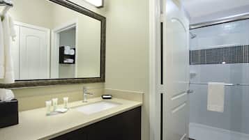 A bathroom with a sink, mirror, and shower.
