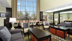 A hotel lobby with a seating area, a reception desk, and a large window with curtains. - Staybridge Suites Houston - Medical Center by IHG (Houston)
