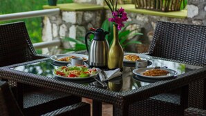 A dining table with plates of food, a coffee pot, and a vase with flowers.