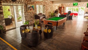 A billiards room with stone walls, a pool table, and rustic wooden furniture.
